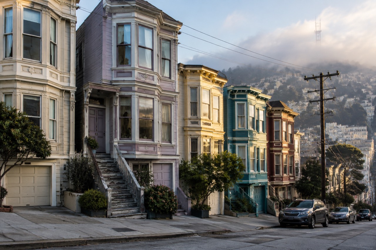Pastel Victorian row house with bay windows on a steep hilly San Francisco street