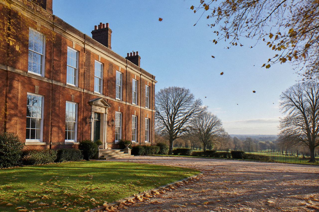 Red-brick Georgian mansion with tall sash windows beside Greenwich Park lawns in morning light