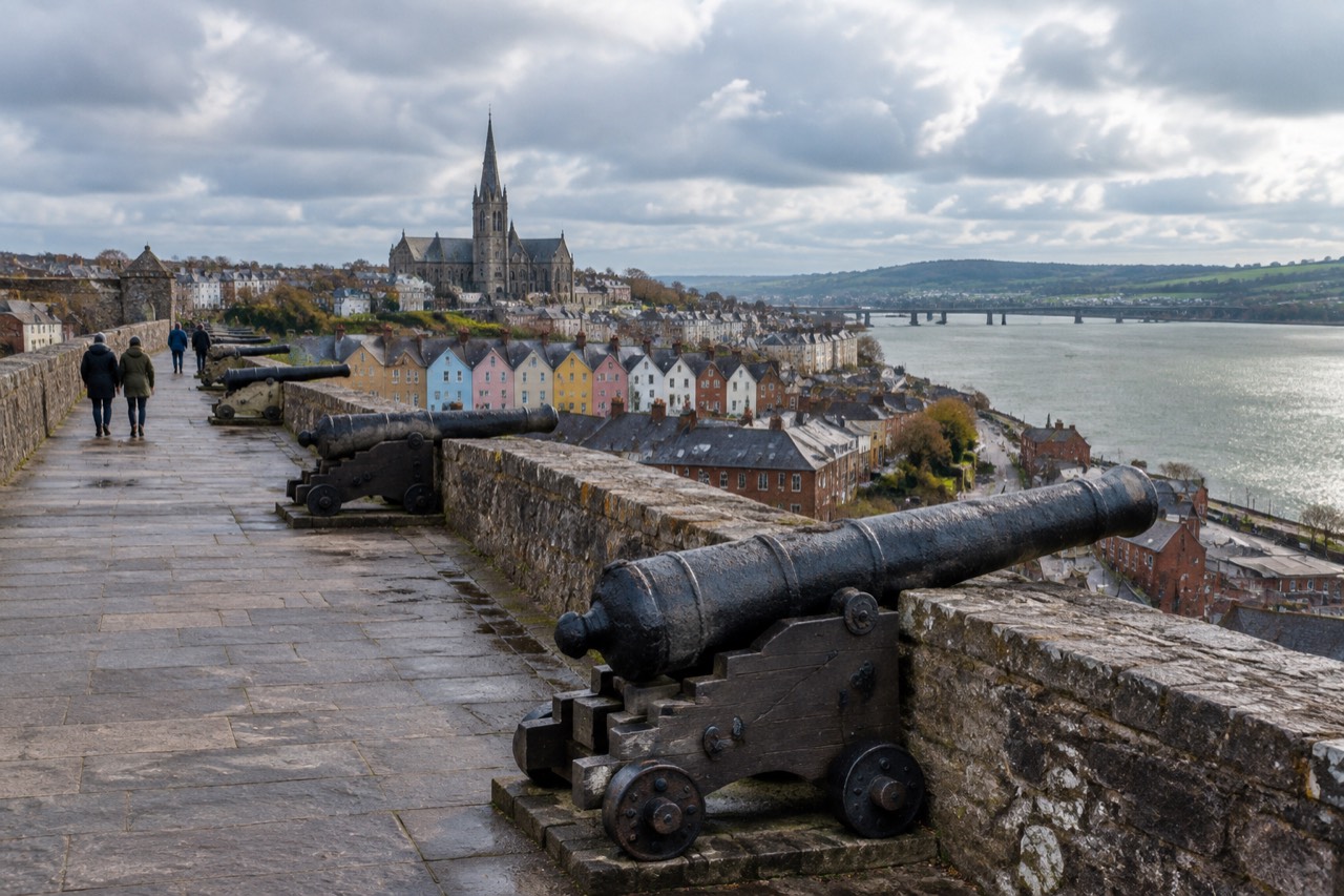 Historic stone city walls above Derry's rooftops, Bogside murals and the River Foyle.