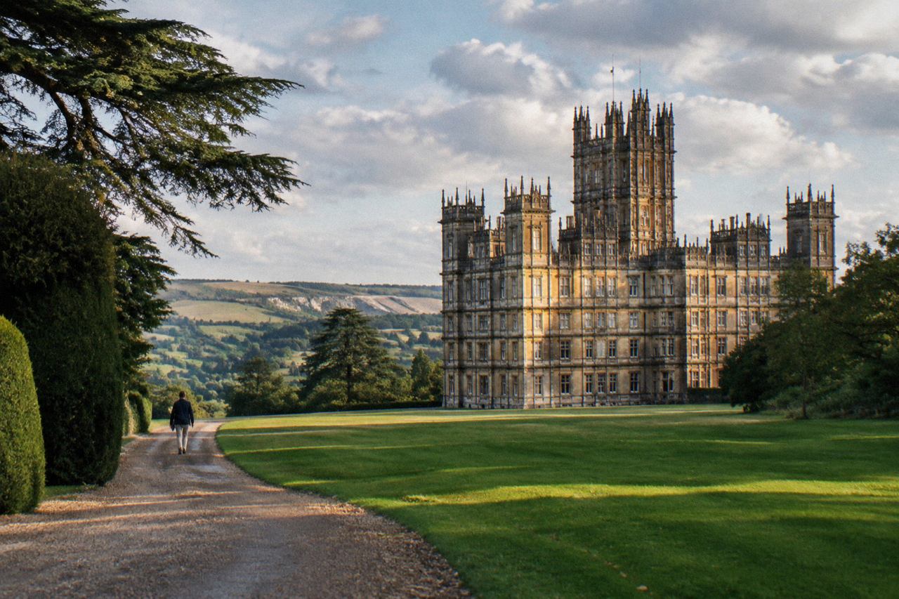 Victorian stone country house with towers above a green lawn and downland
