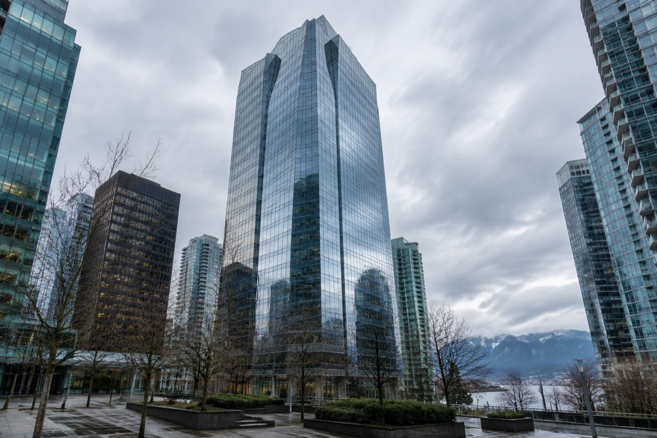 Modern glass office tower reflecting grey sky in downtown Vancouver financial district
