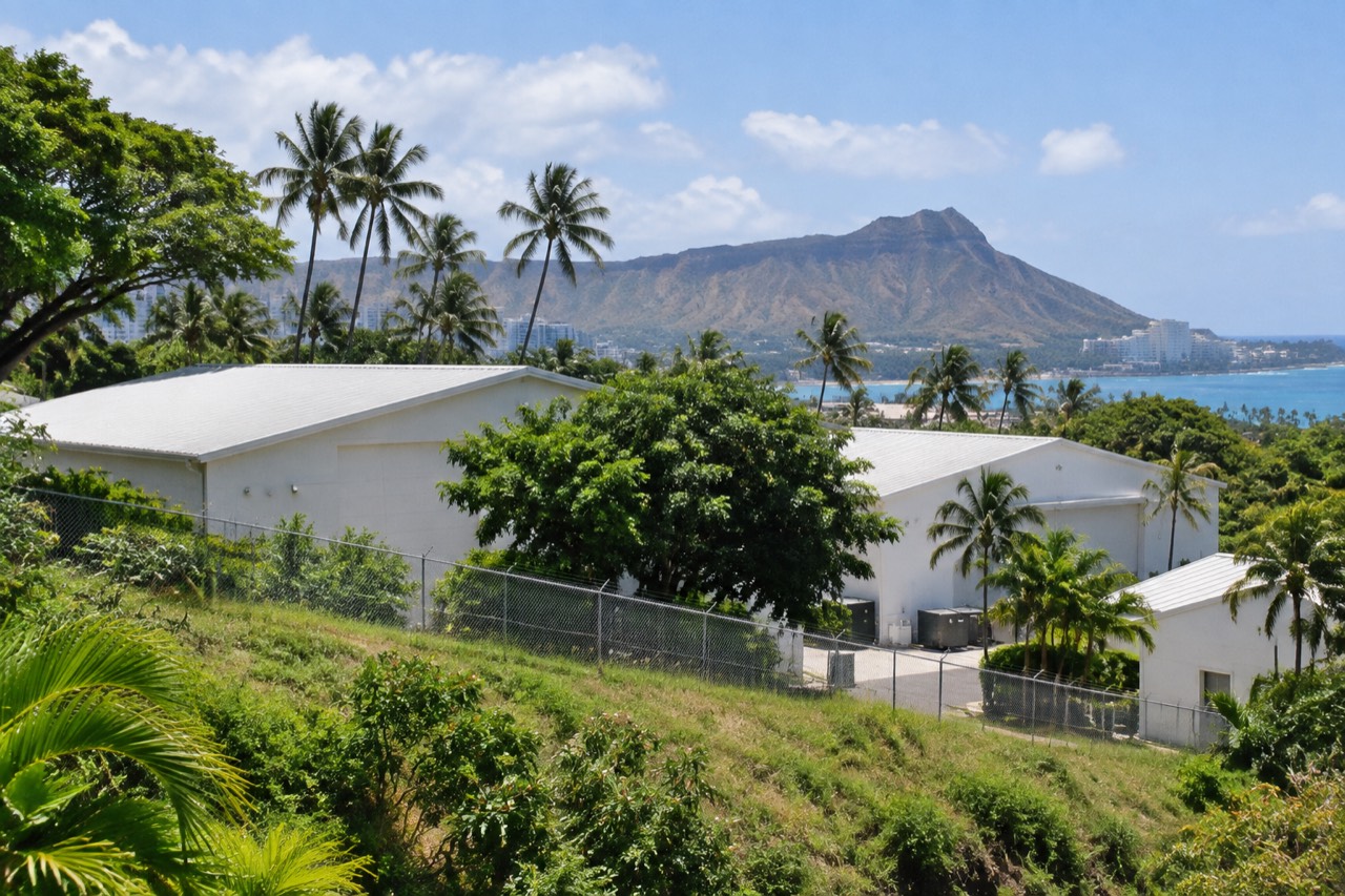 White soundstage buildings behind palm trees with Diamond Head crater in distance