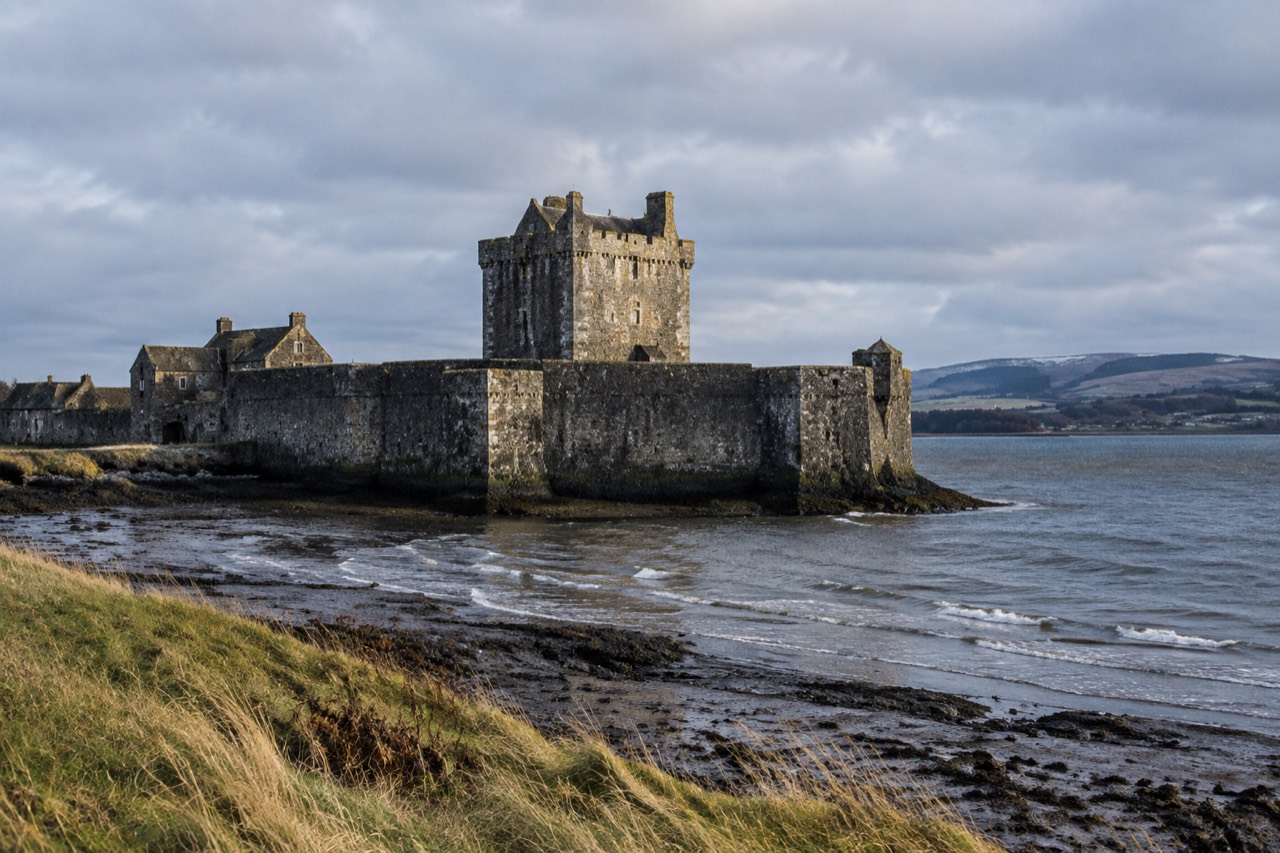 Dark stone castle jutting into the Firth of Forth under a grey winter sky