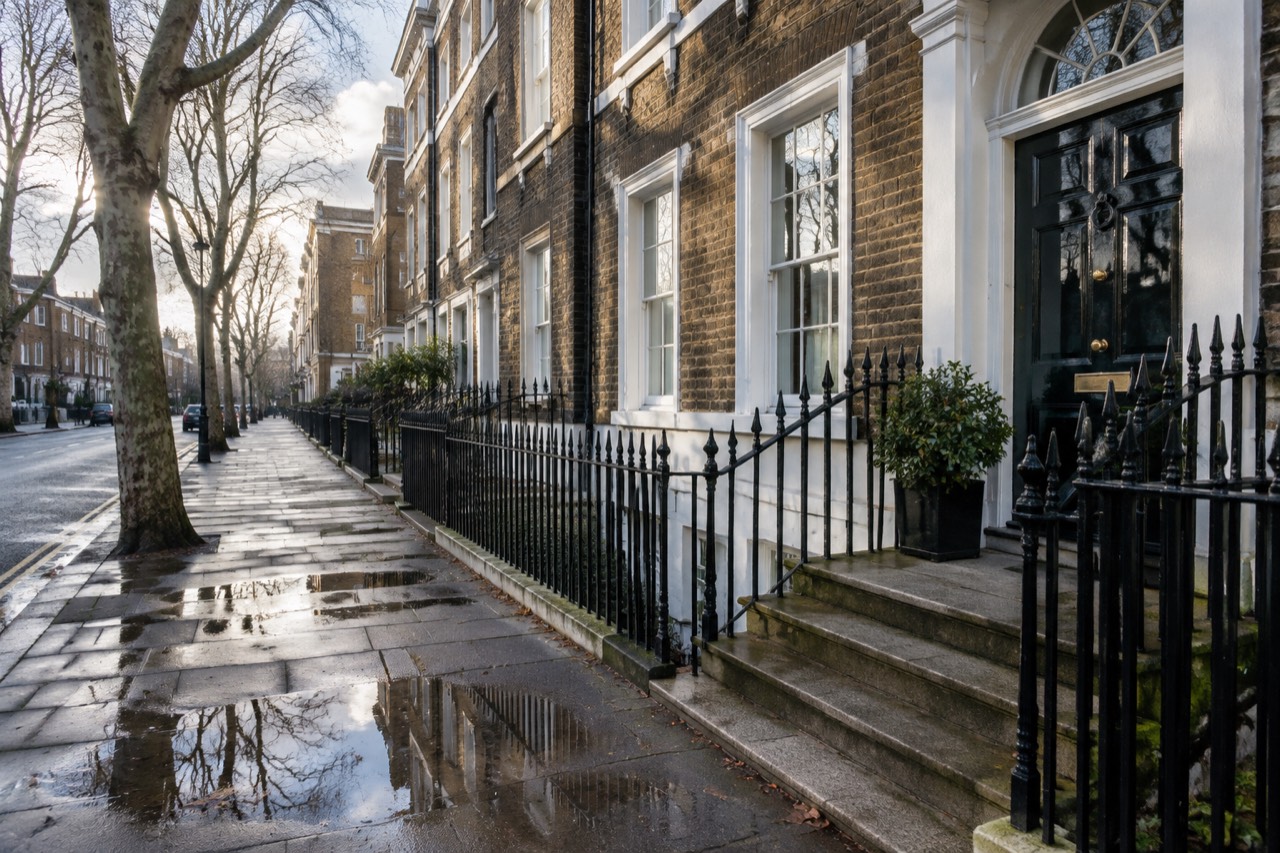 Victorian terraced townhouse with black door and iron railings on a quiet London street