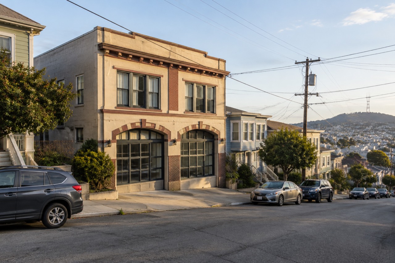 Former San Francisco firehouse building on quiet sloping residential street in afternoon light