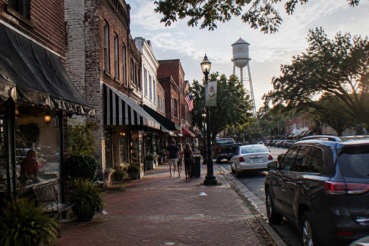 Sunlit red brick main street in small-town Georgia with awnings and a water tower