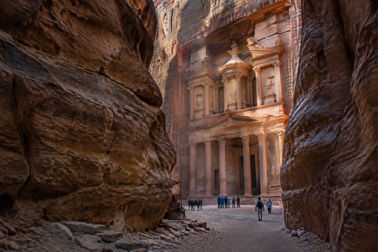 Rose-red carved temple facade glowing at the end of a narrow canyon