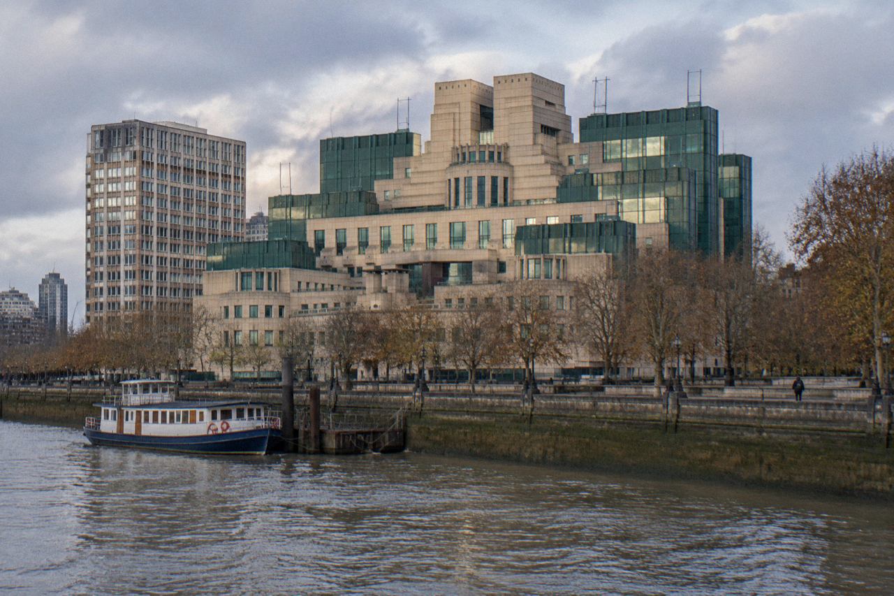 Tiered stone and green glass government building beside the Thames at Vauxhall on an autumn morning.