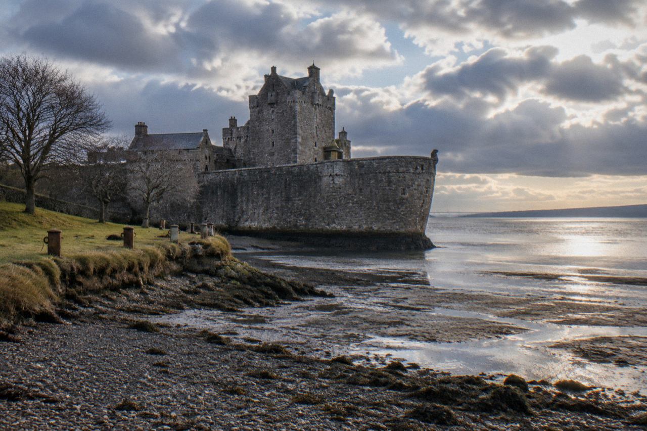 Grey stone fortress on the Firth of Forth shore under moody morning clouds